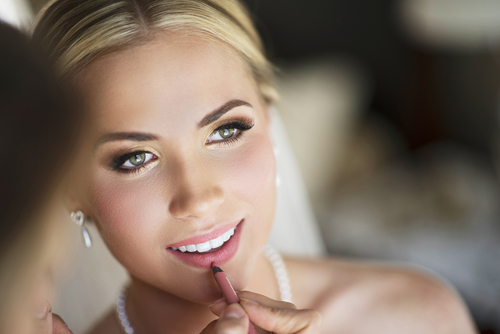 Bride getting makeup applied on wedding day.