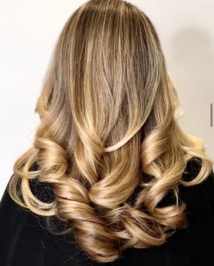Blonde hair with loose, cascading curls.
