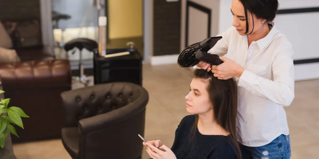 Hairdresser blow-drying woman's hair in salon.