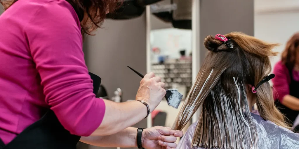 Hairdresser applying hair dye to client.