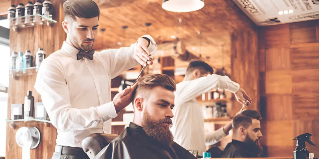 Barber cutting customer's hair in salon.